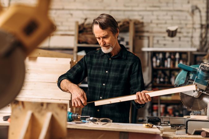 Bearded mature male measuring wooden block