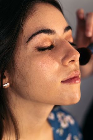 Young woman being made up by a professional makeup artist