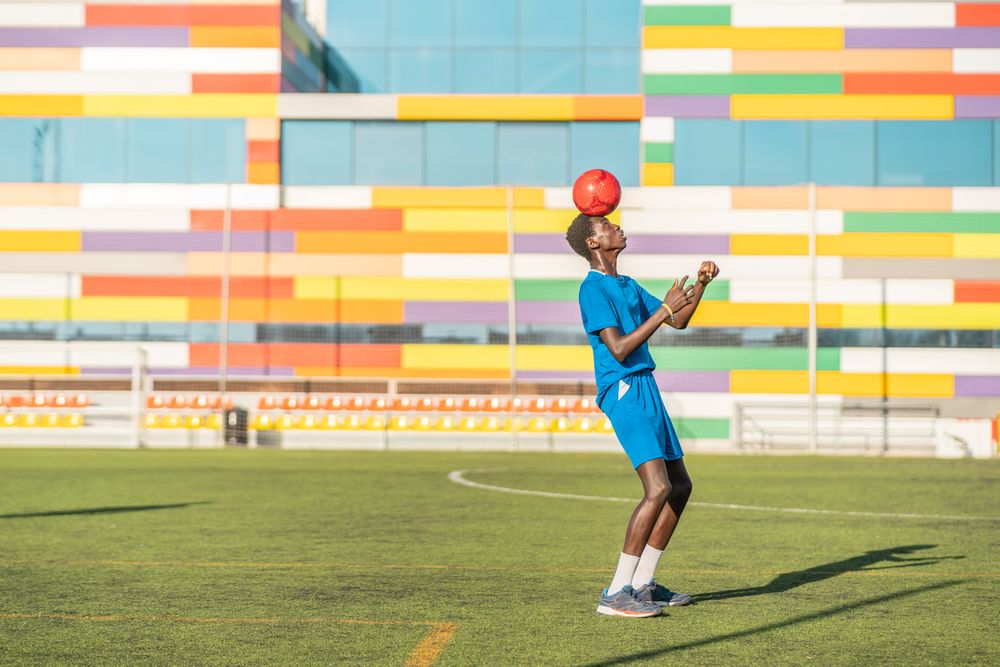 Black teenager jugging football ball on head
