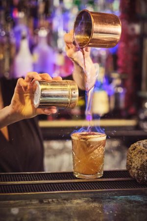 Faceless bartender adding ingredients while preparing burning co
