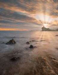 Sundown sky over sea and stony coast