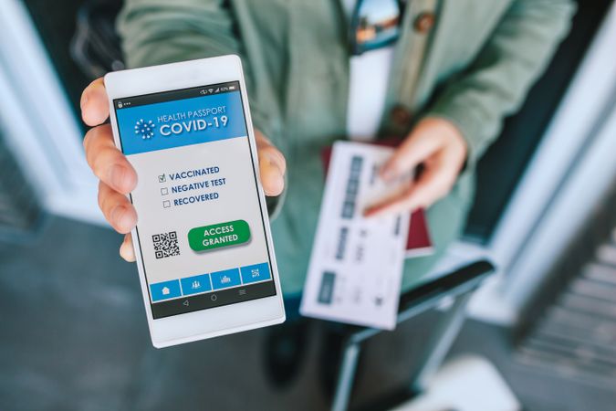 Woman showing covid passport on the smartphone at an airport control