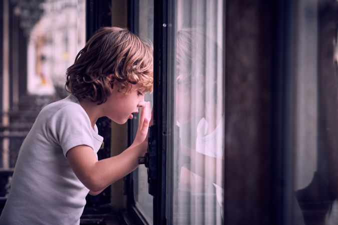 Curious little child looking through window in apartment