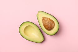 Ripe fresh avocado on pink background, top view