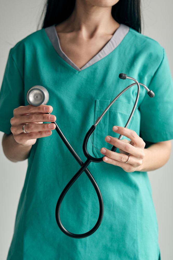 Crop surgeon with stethoscope on light background