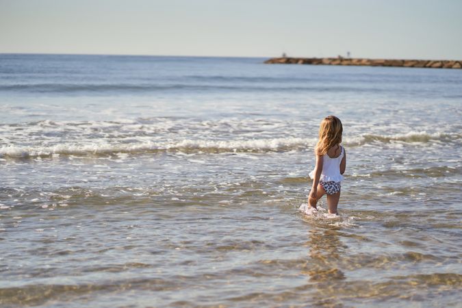 a little girl at the seashore entering the water