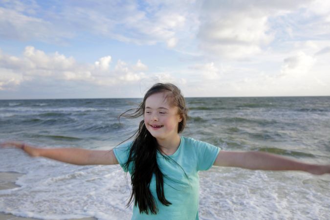 Happy young child twirling on the beach sand