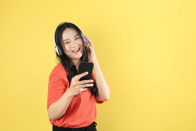 Young Asian Woman Listening to Music from Mobile Phone using Wireless Headphones