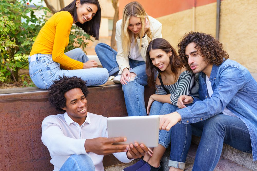 Group of friends gathered around a digital tablet outside