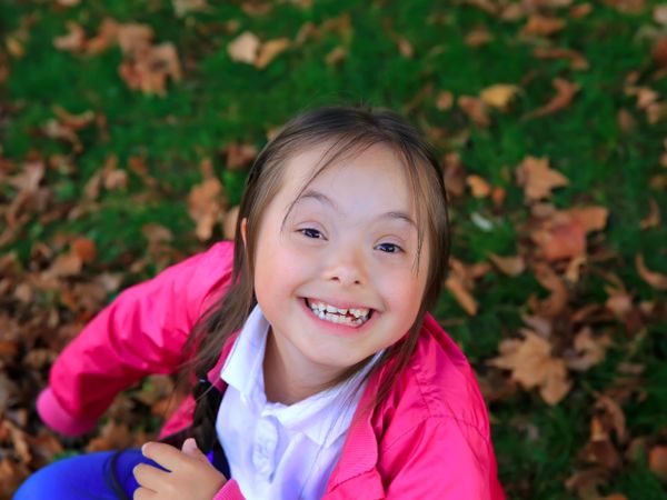 Portrait of happy young girl with Down syndrome in the park on a fall day