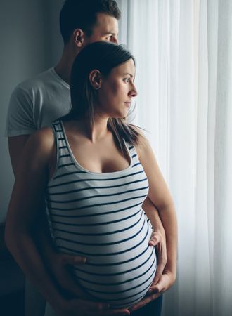Pregnant woman embraced by her husband