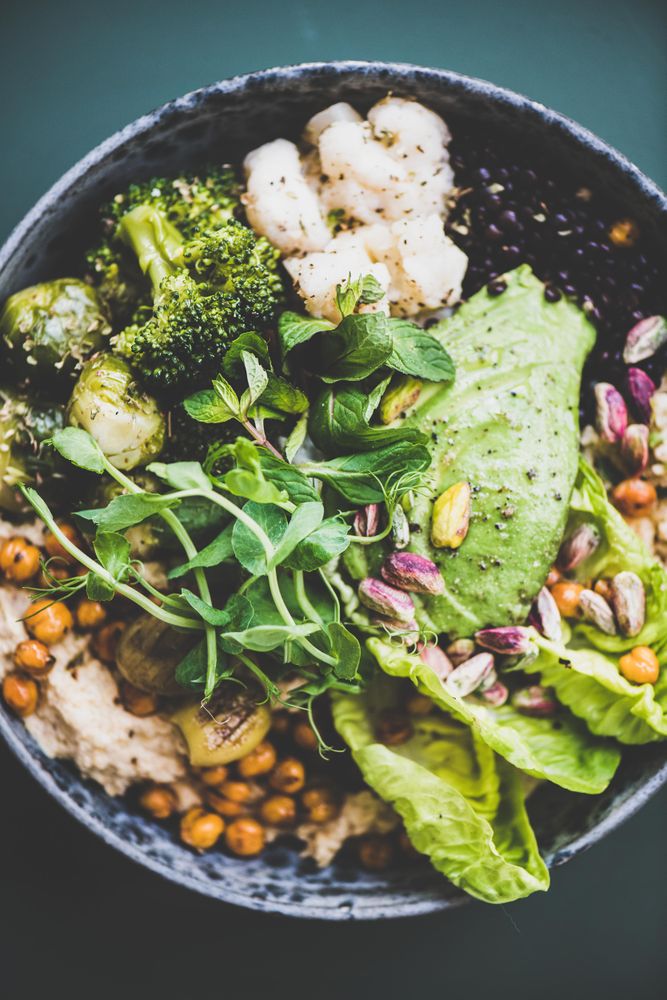 Healthy vegetarian bowl pictured on green surface, close up