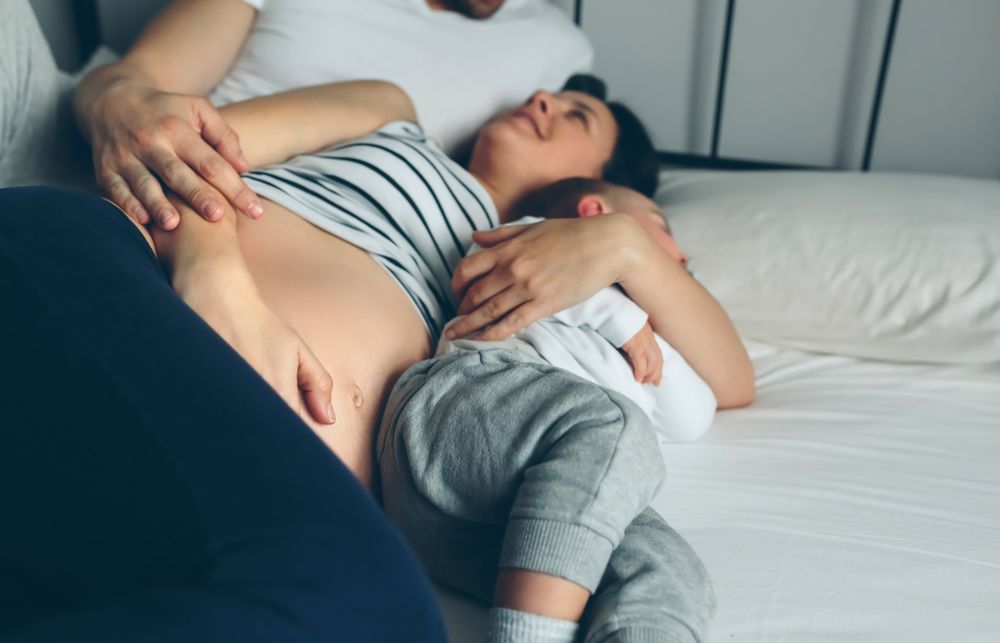 Pregnant woman with man and boy in bed