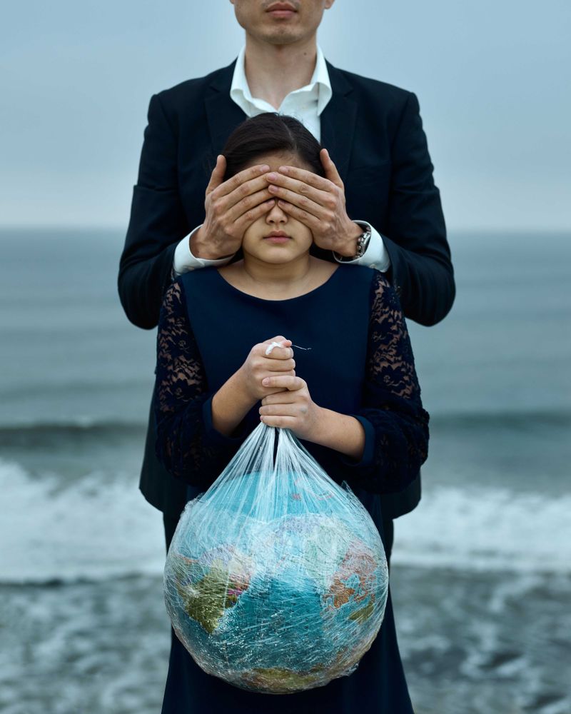 Father closing daughter's eyes who is holding the globe