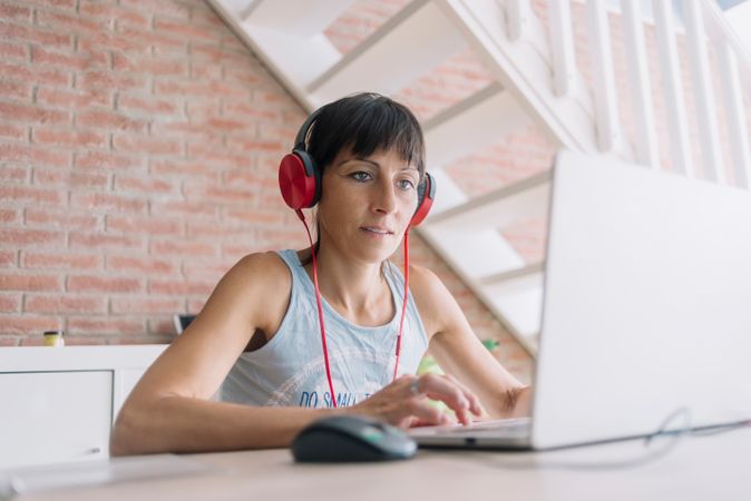 Woman working at laptop wearing red headphones