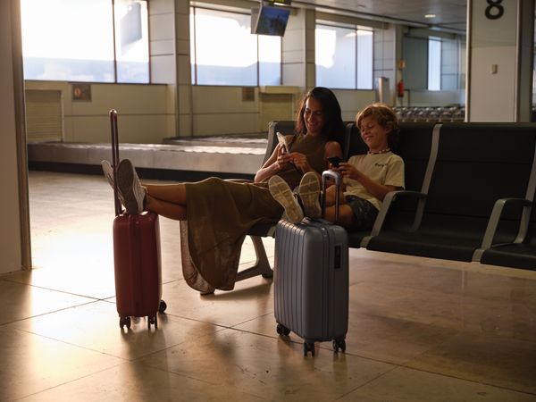 Woman and boy sitting in departure lounge of airport