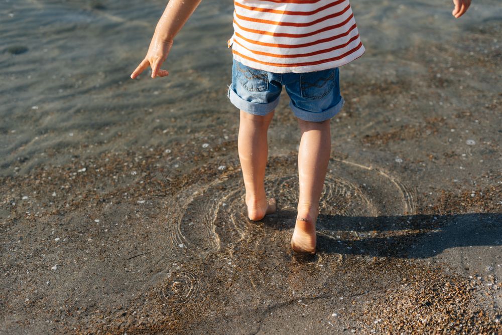 Playful little boy stepping in water