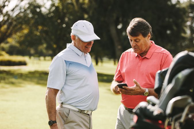 Older man taking break from golfing and using mobile phone