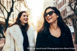 Female friends in warm clothes walking on the city street 5lVvOe