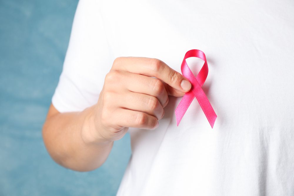 Person in t-shirt hold awareness ribbon against blue background