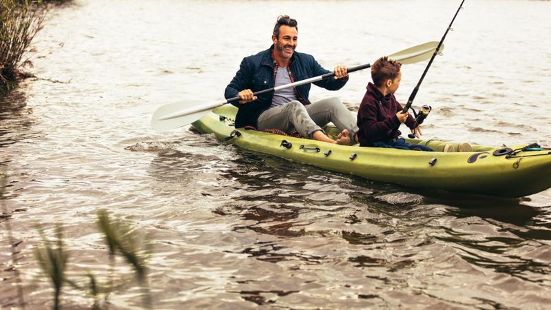 Father and son out to fish in lake sitting in a kayak