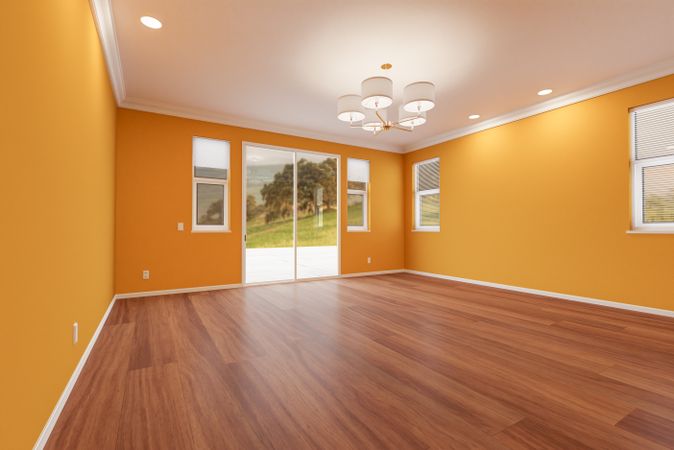 Newly Remodeled Room of House with Finished Wood Floors, Moulding, Yellow Ochre Paint and Ceiling Lights.