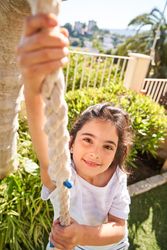 Smiling girl on rope swing in park