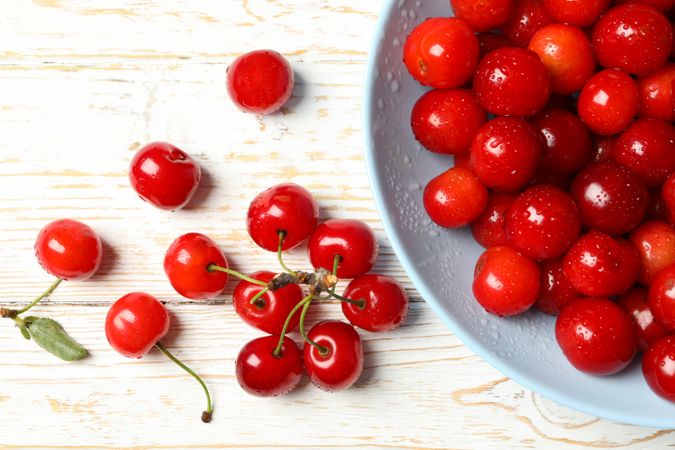 Plate with red cherry on wooden background, top view