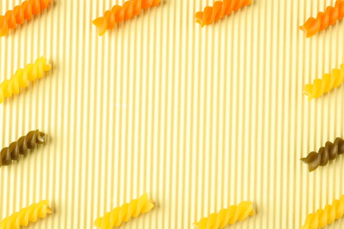 Flat lay composition with color pasta on light background, space for text and closeup