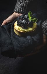 Hand holding a blackberry tartlet