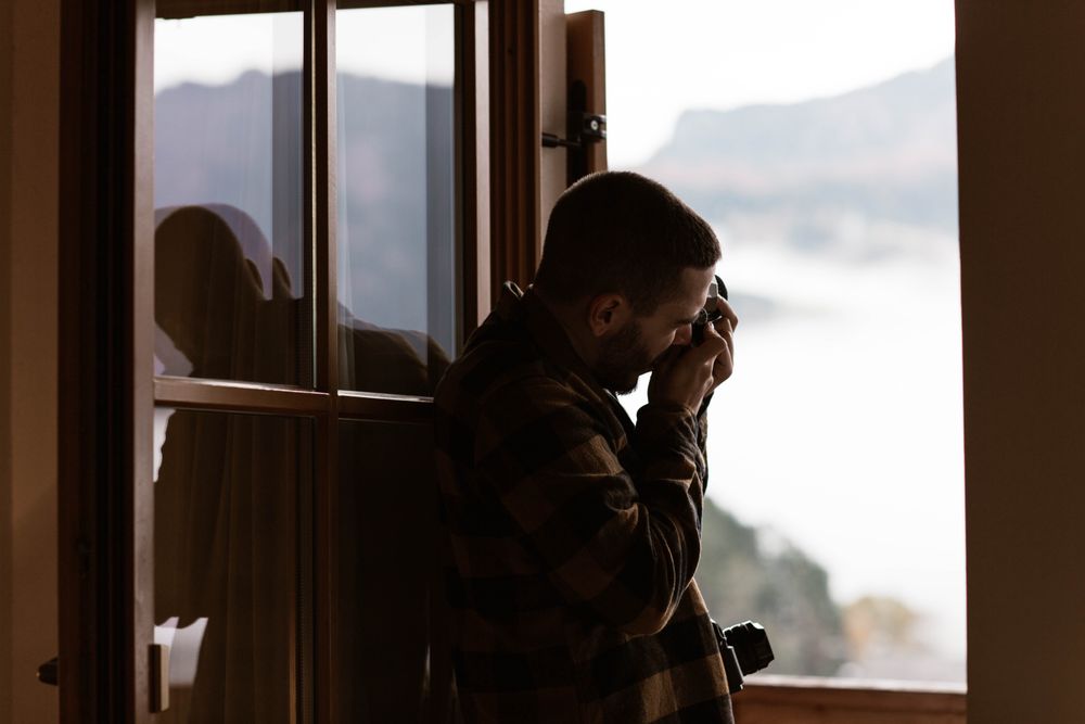 Male photograph in casual wear taking photo from opened window