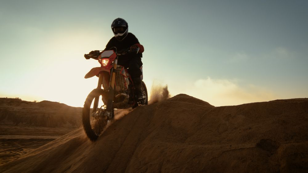 Professional Motocross Motorcycle Rider Driving Over the Dune and Further Down the Off-Road Track.