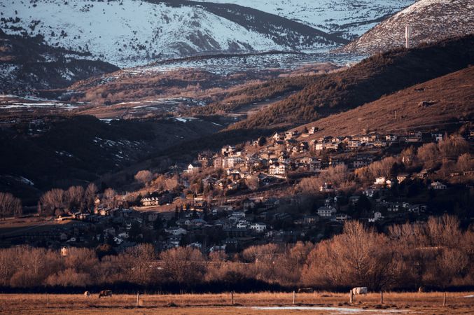 Picturesque view of countryside village in between mountains with forest in snow