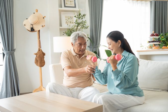 Asian couple exercise with lifting dumbbell for strength training at home