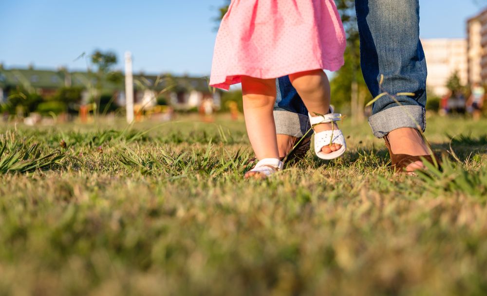 Baby girl learning to walk over a grass park