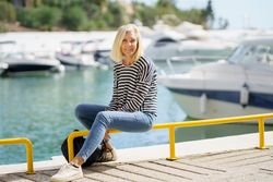 Happy older female sitting on yellow rails of dock