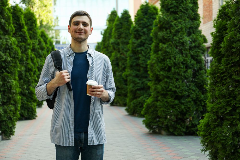 Young student hold backpack and cup of coffee. Study. University