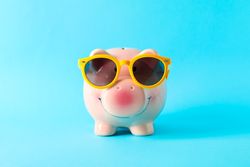Happy piggy bank with sunglasses on color background, space for text. Finance, saving money