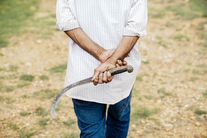 Man with sickle walking along field