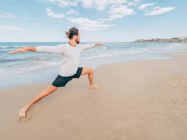 Man training yoga on beach