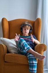 Boy sitting in armchair and learning to make string figures