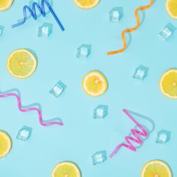 Creative summer background composition with lemon slices, straws and ice cubes