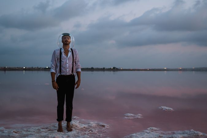 Man with fish tank on head standing at seashore