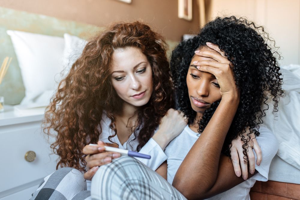Friend comforting a woman displeased with pregnancy test