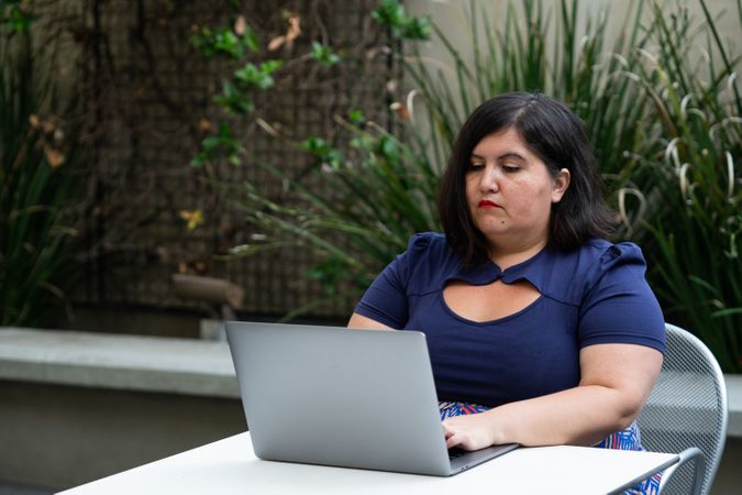 Woman engineer working on code on a patio with plants