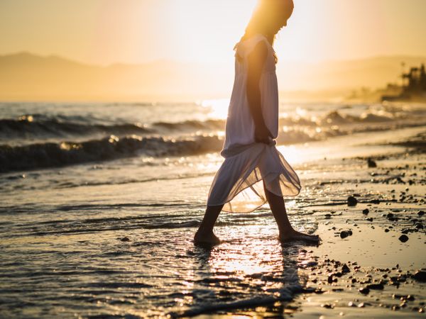 Adorable girl walking on seaside at sunset