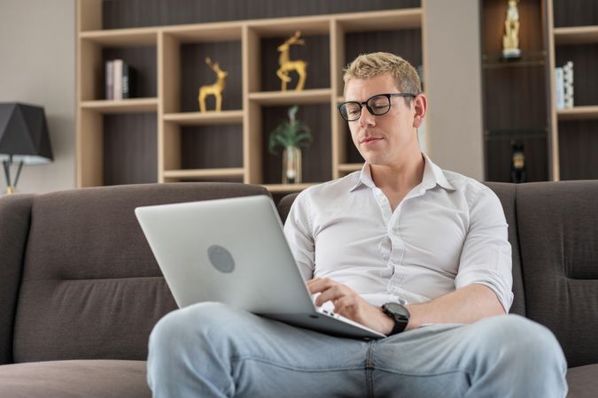 Man using laptop or watching movie on couch in the living room at home