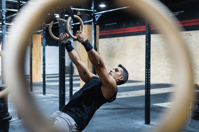 Hispanic sportsman exercising with gymnastic rings