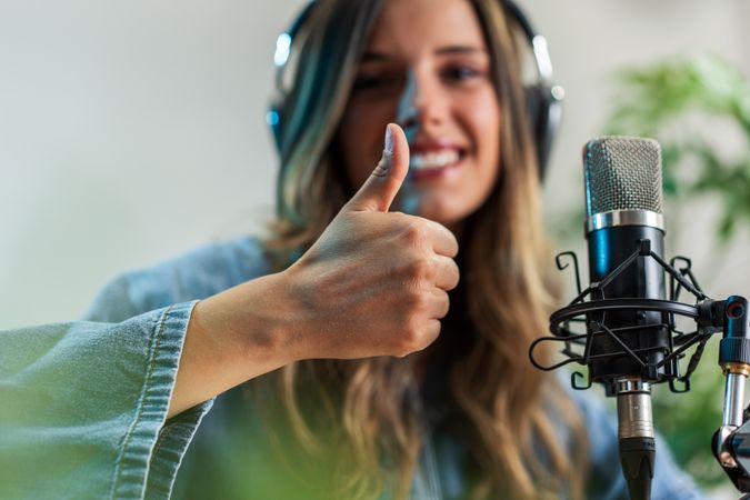 Happy Woman Recording Podcast with Thumbs Up - Smiling positive female vlogger