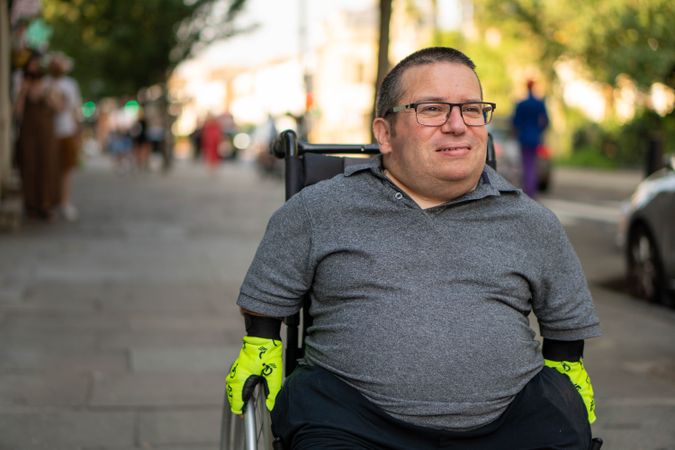 Portrait of smiling man sitting in wheelchair in city street